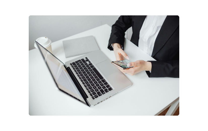 Business professional using a laptop and phone, illustrating SMS marketing and email marketing for business growth.